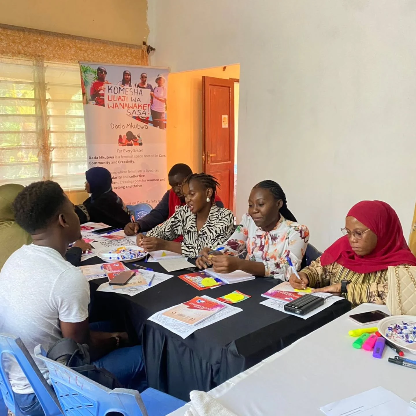 Mentors and participants work together around a table during an L-Care learning session.